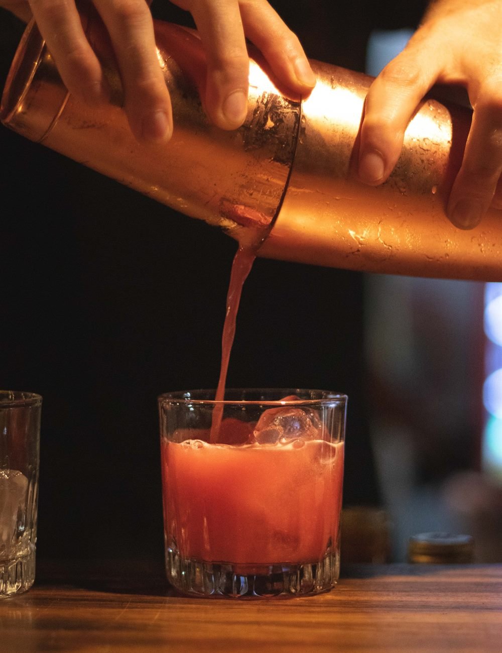 Bartender vaciando un coctel desde una coctelera de cobre